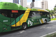 Ônibus a hidrogênio, cor verde e amarelo, trafegando pela via.